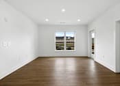 Thumbnail 15 of 44 - A large empty room with a window and wooden floors.