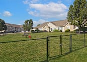 Thumbnail 15 of 21 - A black fence surrounds a green field with houses in the background.