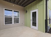 Thumbnail 16 of 44 - A balcony with a white door and a window overlooking a fence.