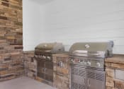 Thumbnail 17 of 35 - two gas bbqs on the patio of a home with white walls and brick at The Enclave at Deer Moss Creek, Florida, 32578