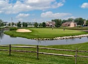 Thumbnail 17 of 21 - A golf course with a pond and a fence.