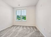 Thumbnail 32 of 51 - A room with a carpeted floor and a window showing a view of trees.