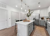 Thumbnail 9 of 25 - A kitchen with a white island and a refrigerator.