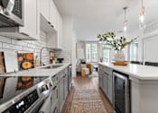 Thumbnail 10 of 25 - A modern kitchen with a large island and a vase of greenery on top.