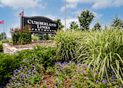 Thumbnail 21 of 21 - A sign for Cumberland Links Apartments is surrounded by greenery and flowers.
