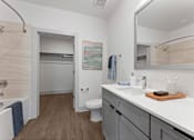Thumbnail 15 of 25 - A bathroom with a white sink, toilet, and a mirror.