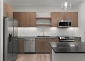 Thumbnail 25 of 52 - A modern kitchen with a stainless steel refrigerator, microwave, and oven.