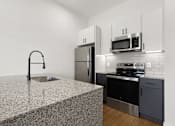Thumbnail 23 of 51 - A kitchen with a granite countertop and stainless steel appliances.