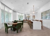 Thumbnail 26 of 35 - a large dining room with a long table and chairs and a kitchen with large windows at The Enclave at Deer Moss Creek, Florida