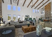 Thumbnail 27 of 51 - A large, modern living room with a stone fireplace and a variety of seating options.