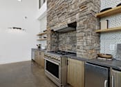 Thumbnail 29 of 51 - A modern kitchen with a stone wall and stainless steel appliances.