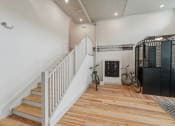 Thumbnail 37 of 46 - a white staircase with a black door and a bike in a room with wood floors