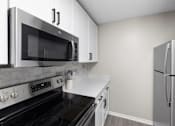 Thumbnail 6 of 67 - A modern kitchen with a black stove top oven and a black microwave above it.