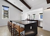 Thumbnail 30 of 51 - A modern kitchen with a black countertop and wooden bar stools.