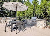 Thumbnail 26 of 50 - A patio with a table and chairs under an umbrella.