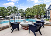 Thumbnail 34 of 45 - A poolside area with a fire pit and lounge chairs.
