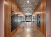 Thumbnail 33 of 51 - A long hallway with wood paneling and black doors on the side.