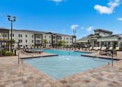 Thumbnail 33 of 35 - a swimming pool with lounge chairs and buildings in the background at The Enclave at Deer Moss Creek, Niceville