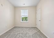 Thumbnail 37 of 51 - A room with a carpeted floor, a window with blinds, and a door.