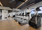 Thumbnail 4 of 51 - A gym with treadmills and a fan.