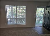 Thumbnail 35 of 45 - A room with a carpeted floor, a sliding glass door, and a wooden door.