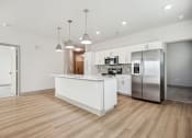 Thumbnail 2 of 31 - a white kitchen with a large island and stainless steel refrigerator at The Falstaff, Raleigh, 27610