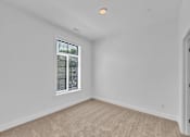 Thumbnail 5 of 25 - A room with a window and carpeted floor.