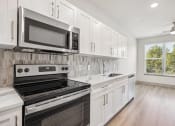 Thumbnail 8 of 31 - a kitchen with white cabinets and black appliances at The Falstaff, Raleigh