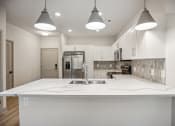 Thumbnail 16 of 31 - a large white kitchen with white marble counter tops and a stainless steel refrigerator at The Falstaff, Raleigh, North Carolina