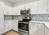 Thumbnail 15 of 31 - a kitchen with white cabinets and a stove and microwave at The Falstaff, North Carolina, 27610