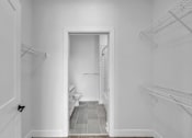 Thumbnail 7 of 25 - A white hallway with a doorway leading to a bathroom.