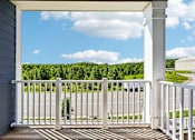 Thumbnail 48 of 51 - A porch with a white railing and a view of a road and trees.