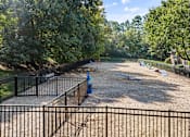Thumbnail 38 of 50 - A black fence surrounds a gravel area with a blue object and a tree.
