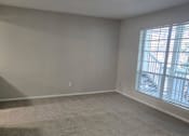 Thumbnail 36 of 45 - A room with a carpeted floor and a window with blinds.