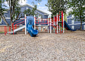 Thumbnail 41 of 45 - A playground with a blue slide and red and white equipment.