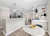 Thumbnail 8 of 45 - A kitchen with a white island and a dining table with a bowl on it.