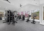 Thumbnail 15 of 50 - A spacious home gym with various exercise equipment and a view of trees outside the window.
