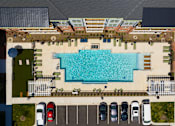 Thumbnail 25 of 40 - An aerial view of a pool surrounded by a parking lot.