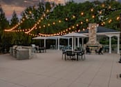 Thumbnail 32 of 50 - A patio with tables and chairs under string lights.