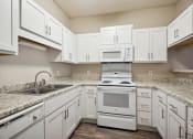 Thumbnail 10 of 46 - a kitchen with white cabinets and white appliances and granite counter tops
