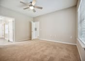 Thumbnail 16 of 46 - an empty living room with carpet and a ceiling fan