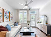 Thumbnail 3 of 25 - A living room with a white couch, a coffee table, and a ceiling fan.