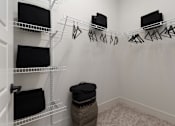 Thumbnail 7 of 52 - A white closet with clothes hanging and shelves.