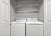 Thumbnail 38 of 67 - Two white washing machines in a white-walled laundry room.