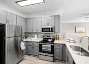 Thumbnail 1 of 45 - A modern kitchen with a stainless steel refrigerator and a stove top oven.