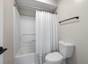 Thumbnail 23 of 67 - A white toilet with a white shower curtain in a bathroom.