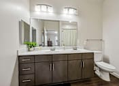 Thumbnail 45 of 51 - A bathroom with a white toilet and a large mirror above a sink.