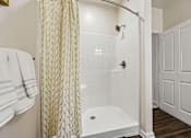 Thumbnail 46 of 51 - A white bathroom with a shower and a towel hanging on the wall.