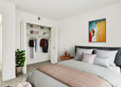 Thumbnail 6 of 14 - A bedroom with a bed, a plant, and a painting on the wall.