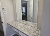 Thumbnail 39 of 45 - A bathroom with a granite countertop and a door.